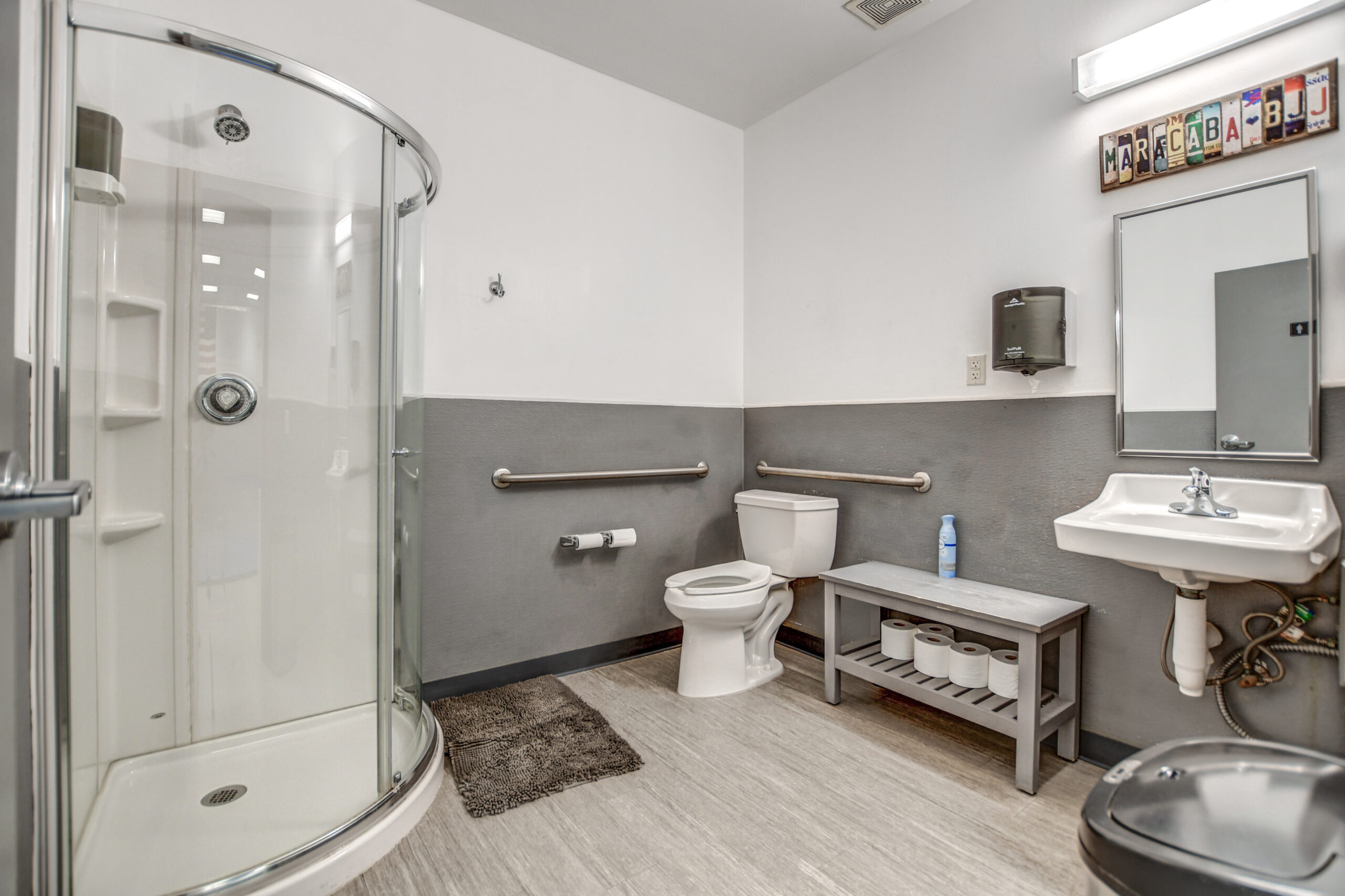 Academy restroom with an enclosed shower, sink, and bench